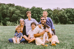 jakir sits with his wife and four sons and puppy in a grassy field